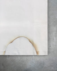 Detail view of burn distressing on I'M NOT NICE I HURT PEOPLE — Baby Tee in vintage white