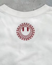 Detail view of Remilia smiley logo on I'M NOT NICE I HURT PEOPLE — Baby Tee in vintage white